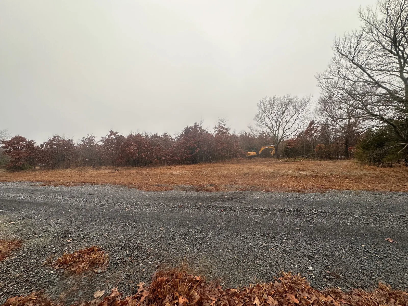 Cleared red dirt ground with a fresh gravel drive after land clearing