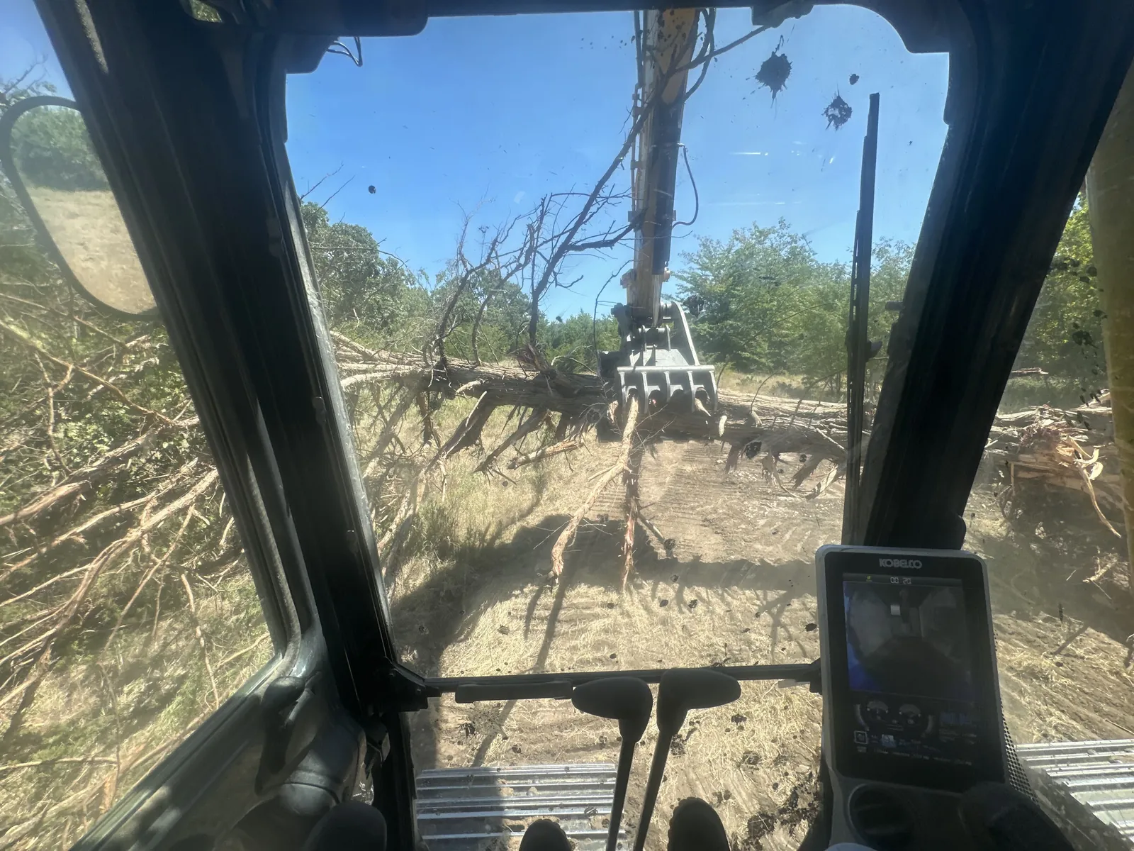 Dozer cab view pushing cleared timber on rural Oklahoma ground