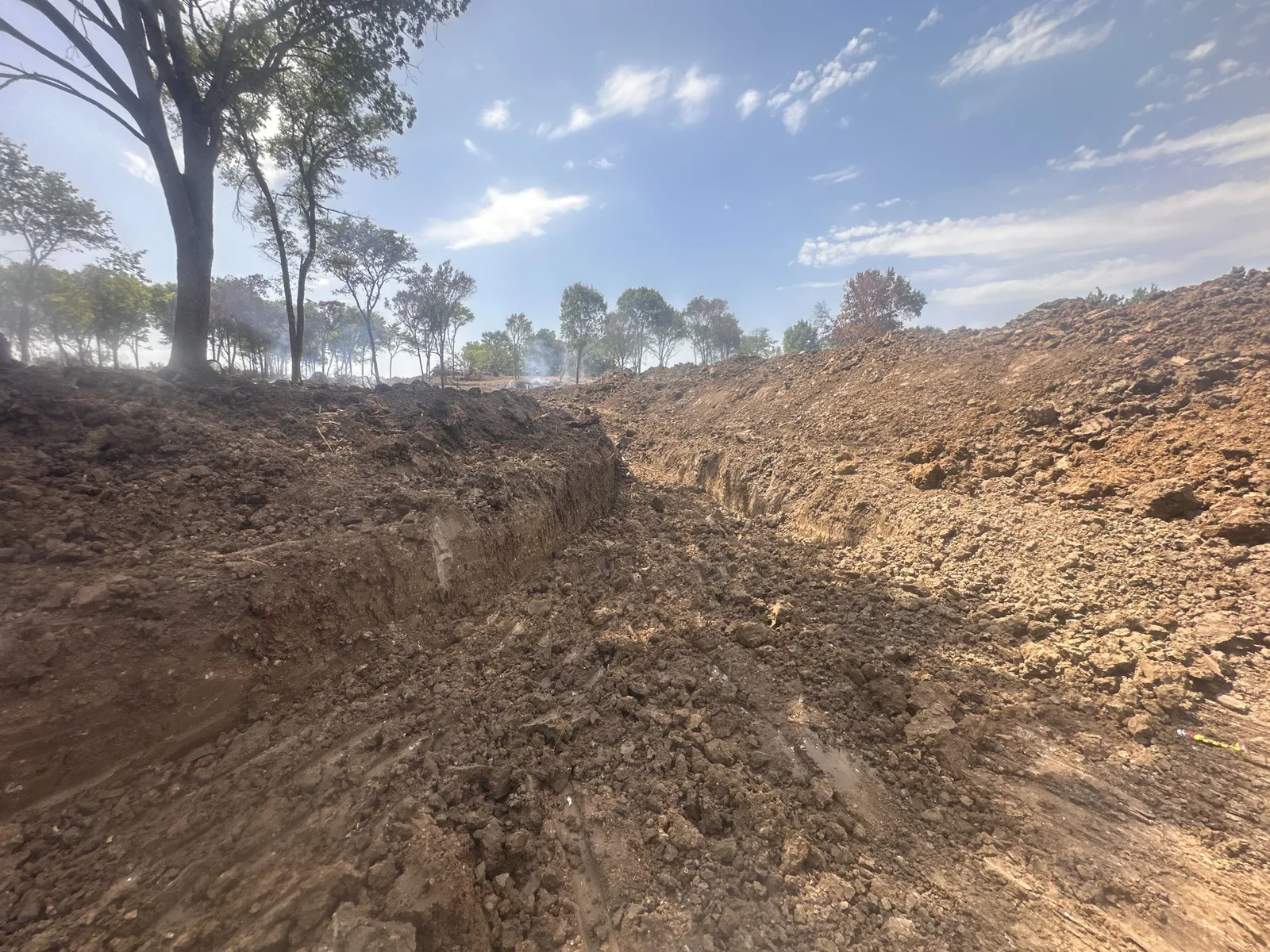 Pond basin cut back with the spoil piled against the tree line on one of our Oklahoma pond jobs