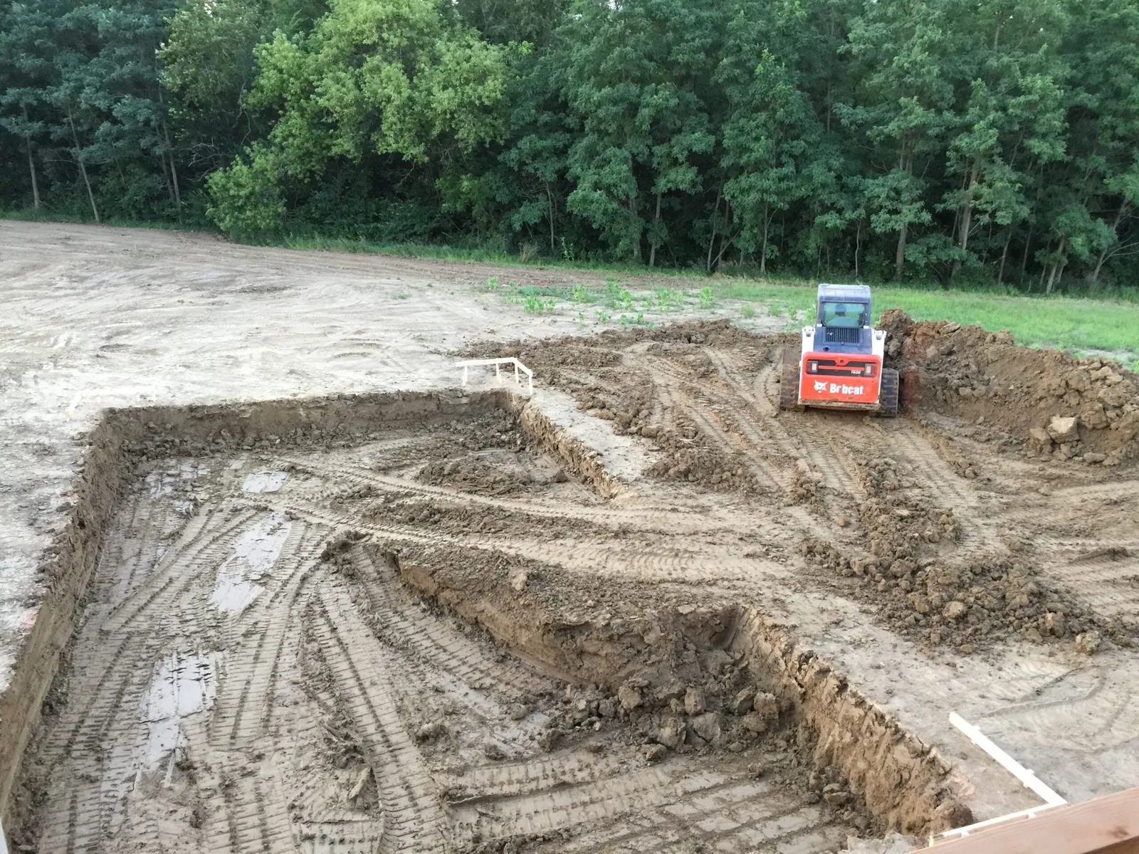 Rectangular pool hole dug out with a skid steer working at the far end