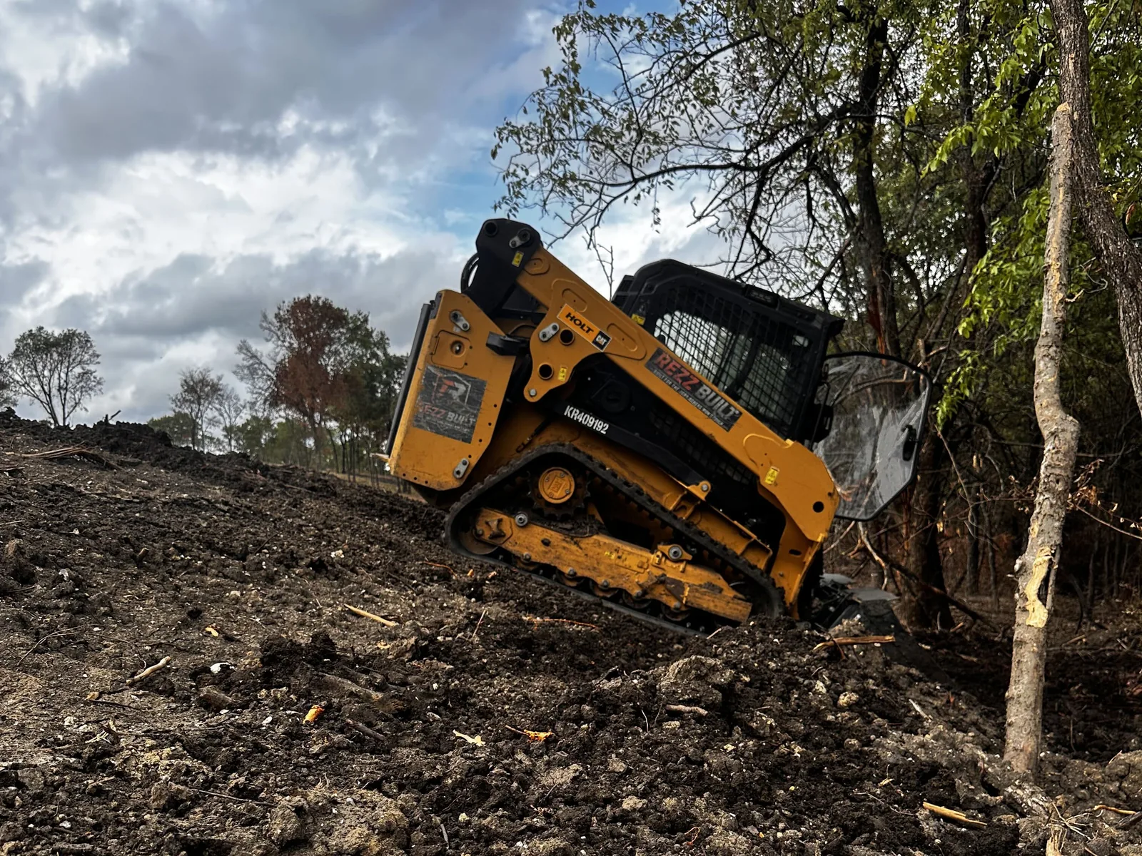 Our tracked skid steer climbing freshly worked dirt on a cleared slope